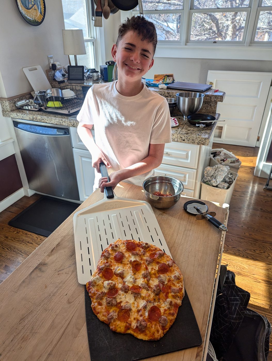 Son holding a finished homemade pizza